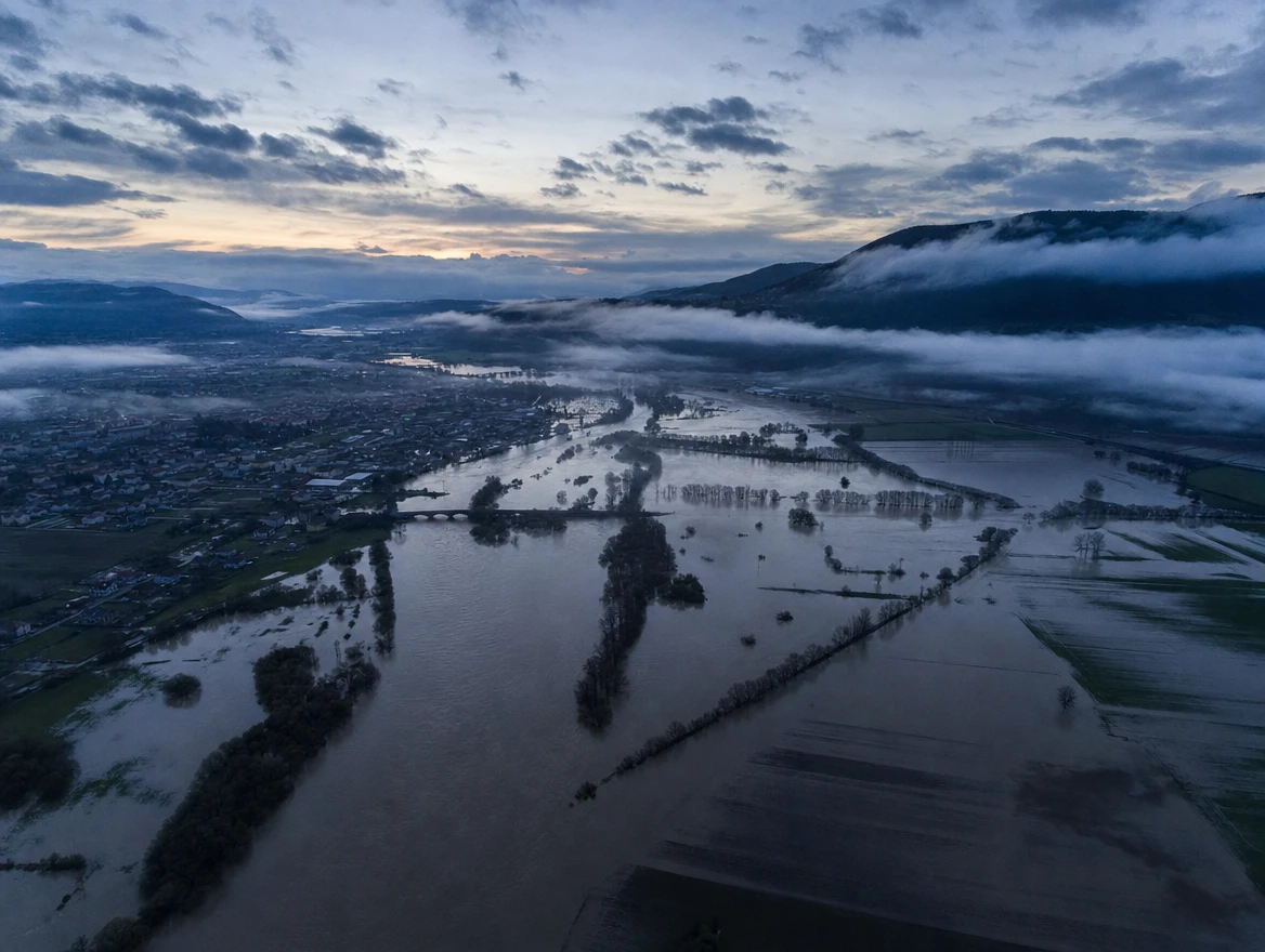 Illustration: A flooded river valley at dawn, seen from above.